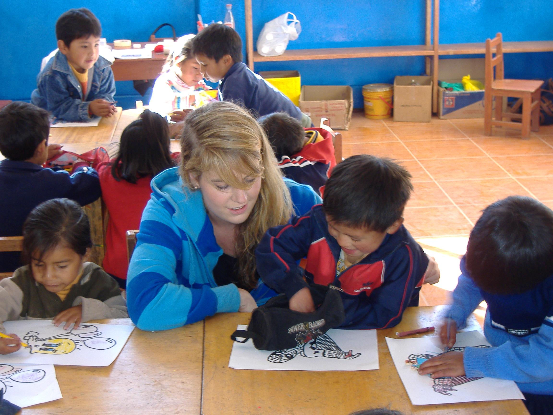 A female Childcare volunteer helps children in a drawing excerise during a Care and Community project in Peru. Projects Abroad Childcare volunteer helps children in Peru draw within a care centre placement.
